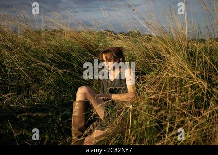 Die Frau sitzt auf dem Feld Stockfoto
