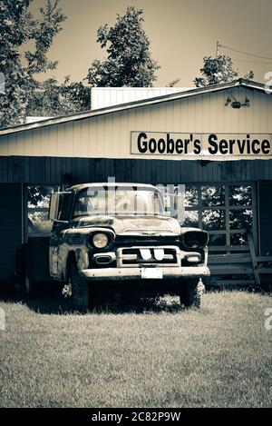 Ein rostiger alter Chevrolet-LKW parkte an der gefälschten Goober's Service Station in der gefälschten Stadt im ländlichen mittleren TN, USA, in Sepia-Ton Stockfoto