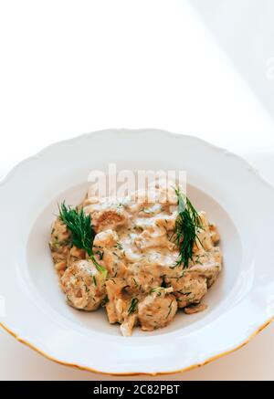 Blick von oben auf weißen Teller mit leckeren Fleischbällchen mit Sauce und Kräutern Stockfoto