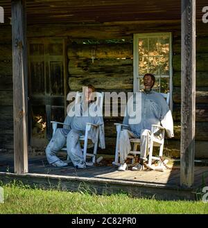 Ein männlicher und weiblicher Schaufensterpuppenkopf mit ausgestopften Körpern in Schaukelstühlen auf der Veranda der gefälschten Hütte in Fake Town, im ländlichen mittleren TN, USA Stockfoto