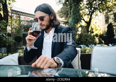 Junge zuversichtlich Brünette bärtige Mann nachdenklich schnüffeln Glas Wein im Restaurant im Freien Stockfoto