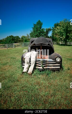 Eine gefälschte Stadtszene eines ausgestopften Dummy in Overalls lehnt sich in die poppte Kapuze auf alten 1930er-Auto in ländlichen grünen Feld in Mittel TN, USA Stockfoto