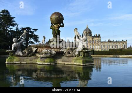 Die Rückseite des Atlas Fountain vor der Südfront von Castle Howard in North Yorkshire. Spiegelungen des Hauses und Brunnen im Wasser Stockfoto