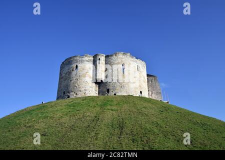 Der Cliffords Tower, Teil des York Castle, steht auf einem grünen Grashügel im Zentrum der Stadt. Der Himmel ist strahlend blau und klar. Ein normannischer Burgfried. Stockfoto