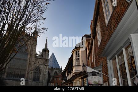 Das östliche Ende des York Minster von der College Street aus gesehen. Altmodische Backsteingebäude im Tudor-Stil überhängen die Straße unten. York, England. Stockfoto