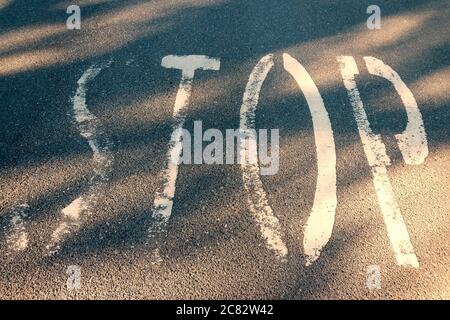 Stop Wort auf Asphalt. Warnzeichen auf Autobahnmasse geschrieben. Die Buchstaben der Verkehrssicherheit färben auf der Fahrbahn. Grunge Text auf Transportboden. Conceptua Stockfoto