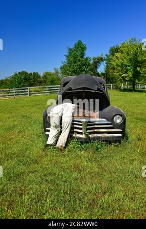 Eine gefälschte Stadtszene eines ausgestopften Dummy in Overalls lehnt sich in die poppte Kapuze auf alten 1930er-Auto in ländlichen grünen Feld in Mittel TN, USA Stockfoto