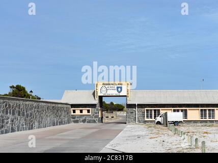 Das Eingangsschild zur Robben Insel, ein UNESCO-Weltkulturerbe. Das Schild ist über einer Fahrbahn und neben verschiedenen Gebäuden gegen einen blauen Himmel. Stockfoto