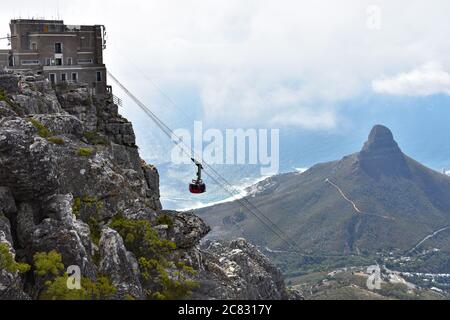 Blick auf die Seilbahn, wenn sie die obere Seilbahnstation am Tafelberg erreicht. Lions Head Berg und der Atlantische Ozean sind im Hintergrund zu sehen Stockfoto