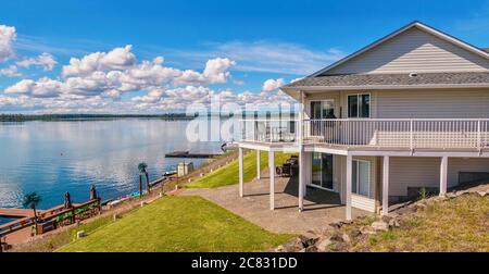Weitwinkel Blick auf ein wunderschönes, großes modernes Luxus-Sommerferienhaus, mit Sonnenterrassen, Glasgeländern und großen Fenstern, in British Columbia. Stockfoto