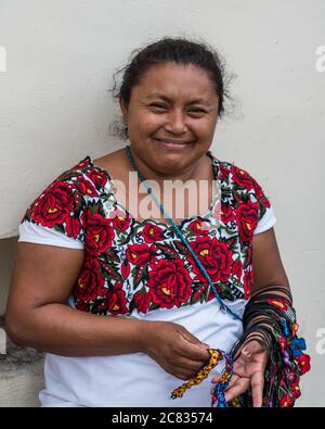 Eine Maya-Frau in ihrem traditionellen bestickten Huipil, die auf der Straße in Valladolid, Yucatan, Mexiko, Kunsthandwerk verkauft. Stockfoto