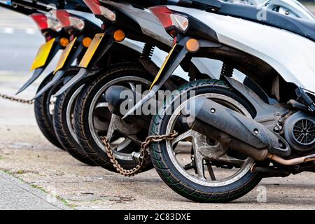 Die Hinterräder des Pizza Delivery roller Chain sind mit einer anti-Diebstahl-Kette-gesperrten Image Stockfoto