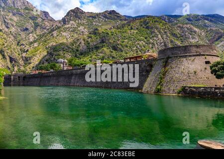 Smaragdgrüne Wasser der Bucht von Kotor oder Boka Kotorska, Berge und das alte steinerne Stadtmauer von Kotor ehemalige venezianische Festung in Montenegro Stockfoto