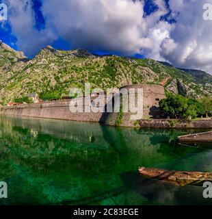 Smaragdgrüne Wasser der Bucht von Kotor oder Boka Kotorska, Berge und das alte steinerne Stadtmauer von Kotor ehemalige venezianische Festung in Montenegro Stockfoto