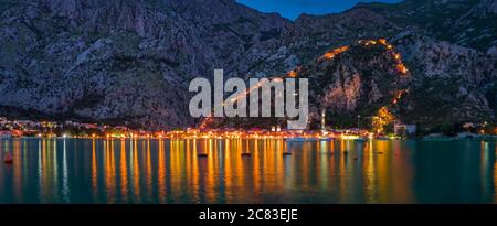 Sonnenuntergang von Kotor Bucht oder Boka Kotorska mit einer beleuchteten alten Festung Stadtmauer in den Bergen, dem Balkan, Montenegro an der Adria Stockfoto