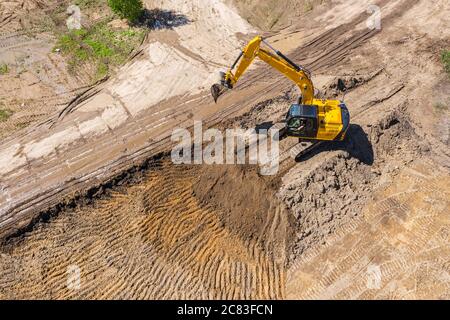 Gelber Industriebagger, der auf der Baustelle arbeitet. Luftaufnahme von fliegender Drohne Stockfoto