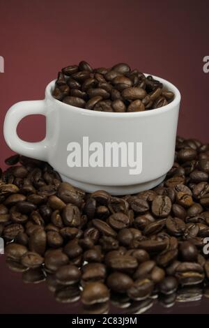 Weiße Tasse mit Kaffeesorten bestreut mit Kaffeesorten auf einem Hintergrund Stockfoto
