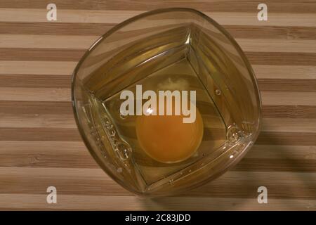 Rohes Ei in einem Glasbecher. Auf schwarzem Hintergrund Stockfoto