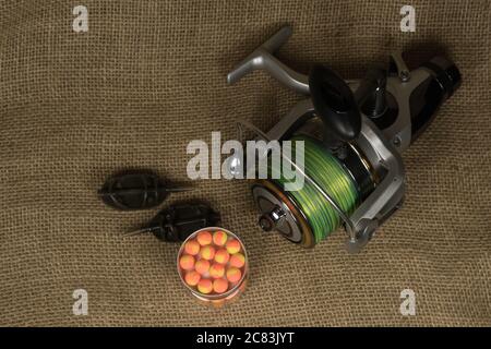 Angeln, Karpfenrolle mit Angellinel auf dem Hintergrund von Sackleinen . Sackleinen Stockfoto