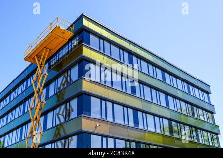 Moderne Gebäudefassade Reparatur mit einem hohen Scherenlift mit einer Plattform Stockfoto