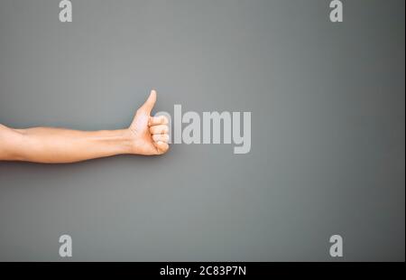 Männlich linke Hand geben Daumen nach oben wie Konzept isoliert auf grauem Hintergrund. Stockfoto