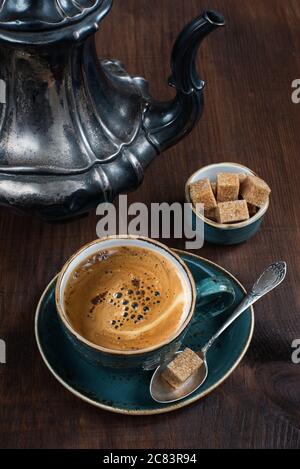 Schwarzer Kaffee in der blauen Vintage Tasse und antike silberne Kaffeekanne auf alten dunklen Holzbrettern Stockfoto