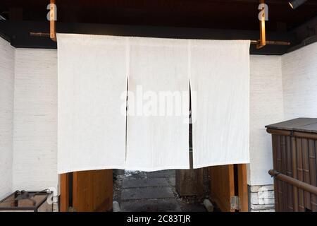 Der Vorhang-ähnliche Stoff, der vor traditionellen japanischen Restaurants und Geschäften hängt, dient nicht nur als Schild, sondern hat eine größere Bedeutung, Stockfoto