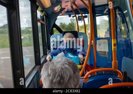 Menschen mit Gesichtsmasken sitzen auf einer Busfahrt sitzen auseinander während soziale Distanz Regeln Stockfoto