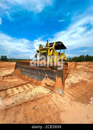 Gelbe Bulldozer auf dem Sand, mit einem hellen schönen blauen Himmel auf dem Hintergrund Stockfoto