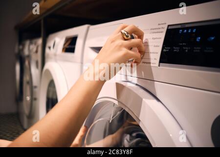 Close up Mädchen einschalten Waschmaschine in Self-Service-Wäscherei Stockfoto