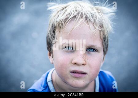 Portrait eines lustigen glücklich schelmisch fröhlich niedlich blonde blauäugige Junge machen Sommersprossen schmutziges Gesicht beim Spielen, lachen. Kindergarten, glückliche Kindheit Stockfoto