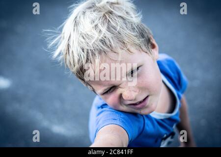 Portrait eines lustigen glücklich schelmisch fröhlich niedlich blonde blauäugige Junge machen Sommersprossen schmutziges Gesicht beim Spielen, lachen. Kindergarten, glückliche Kindheit Stockfoto