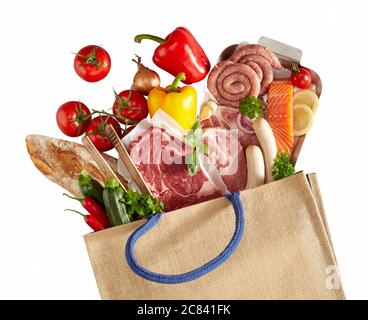 Frische Lebensmittel in einer flachen Stillleben verschüttet aus einem wiederverwendbaren Einkaufstasche mit verschiedenen rohen Fleisch, Gemüse, Baguette, Lachs, Wurst, Kräuter a Stockfoto