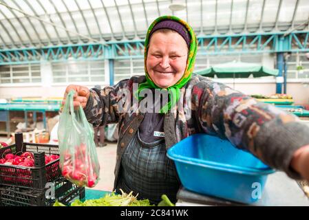 Iasi / Rumänien - 14. Mai 2020: Erwachsene rumänin mit traditionellem Kopftuch gebündelt um den Kopf Verkauf von Gemüse auf dem Bauernmarkt Stockfoto