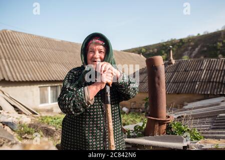 Trebujeni / Moldawien - 15. Mai 2020: Porträt einer erwachsenen moldawien Frau mit traditionellem Kopftuch, das Schaufel in ländlicher Umgebung hält Stockfoto