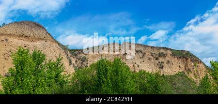 Hohe Lehmklippe an hellen sonnigen Tag auf blauem Himmel Hintergrund Stockfoto