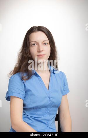 Mittelschenkel abgeschnitten Studio-Porträt von jungen ziemlich langhaarige Frau in blauem Kleid isoliert auf weiß. Sie scheint ruhig und ernsthaft in die Kamera zu schauen. Peo Stockfoto