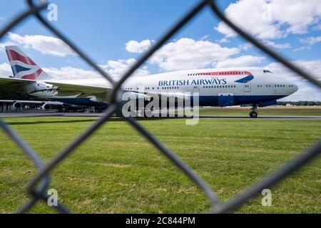 British Airways hat vor kurzem den Rücktritt von seiner Flotte von 747 Flugzeugen angekündigt, eine Entscheidung, die aufgrund der Auswirkungen der Coronavirus-Pandemie nach vorne gebracht wurde. Diese BA 747 ist auf Kemble Flugplatz, Gloucestershire mit Es Motoren schon entfernt geparkt. Auf dem Flugplatz 'Air Salvage international' befindet sich ein Luftfrachtschlauch für Teile und Schrott. Stockfoto