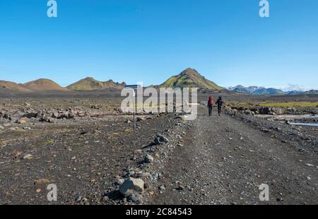 Isländische Lavawüste Landschaft mit zwei Mann Wanderer über Fußgängerbrücke Auf Innri-Emstruraon auf Laugavegur Wanderweg mit Blick auf Tindfjallajokull Stockfoto