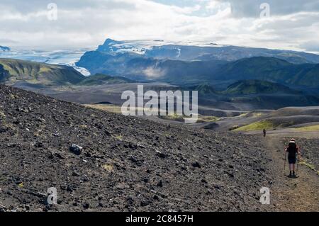 Isländische Lavawüstenlandschaft mit Tindfjallajokull Gletscher und zwei Wanderern auf Laugavegur Wanderweg. Fjallabak Nature Reserve, Island. Sommer Stockfoto
