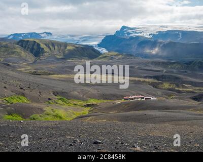 Botnar Hütte und Campingplatz auf Laugavegur Wanderweg, grünes Tal in vulkanischer Landschaft zwischen Lavafeldern mit Blick auf Myrdalsjokull Gletscher Stockfoto