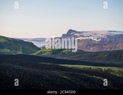 Sonnenaufgang auf Botnar Campingplatz bei Island auf Laugavegur Wanderweg, grünes Tal in vulkanischer Landschaft mit Blick auf Myrdalsjokull Gletscher. Am frühen Morgen Stockfoto