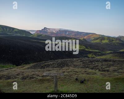 Hölzerner Touristenposten mit Schild Thosmork auf Botnar Campingplatz in Island auf Laugavegur Wanderweg, grünes Tal in vulkanischer Landschaft zwischen Lavafeldern Stockfoto