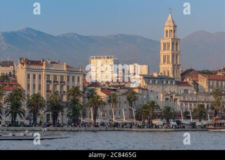Split, Kroatien - 15 2018. August: Abendsonne wirft ein warmes Licht über Meer und Promenade von Split, Berge & Glockenturm von Saint Dominus sichtbar. Stockfoto