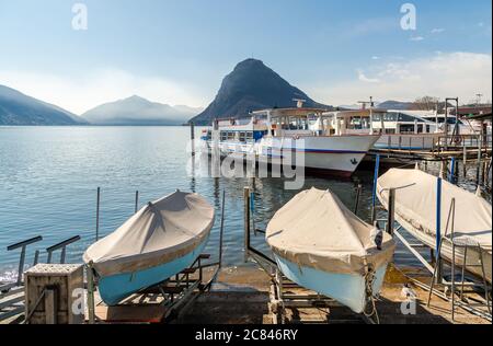 Landschaft des Luganersees mit Booten am Pier und Monte San Salvatore, Lugano, Schweiz Stockfoto