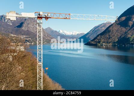 Industriebaukran auf dem Hintergrund des Sees und der Berge. Stockfoto