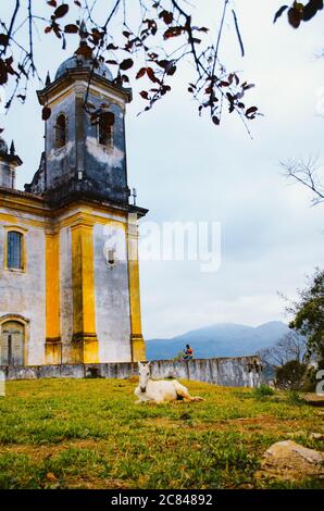 Seitenansicht der Nossa Senhora das Mercês e Perdões Kirche in Ouro Preto, Minas Gerais, in einem bewölkten Nachmittag mit Hügeln im Hintergrund. Stockfoto