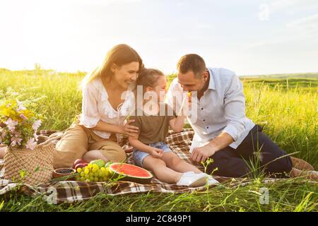 Kleine Tochter füttert ihren Vater mit Traube Stockfoto