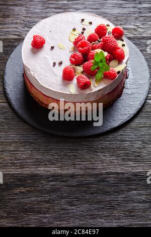 himbeer-Eiskuchen auf Schieferplatte auf dunklem Holztisch, vertikale Ansicht von oben Stockfoto