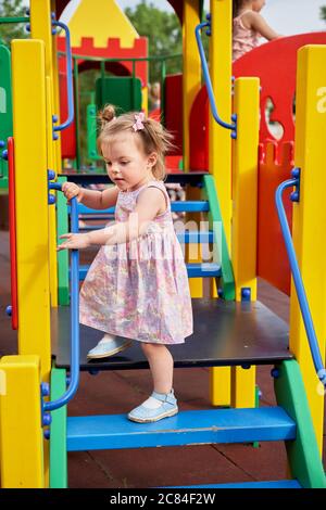 Ein kleines Mädchen mit zwei Schwänzen spielt auf dem Spielplatz Stockfoto